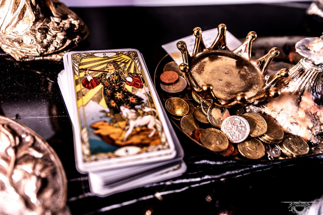 Tarot deck beside a golden crown dish full of coins