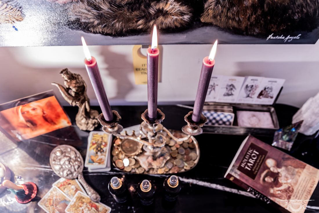 Three purple candles burning on Mia's altar