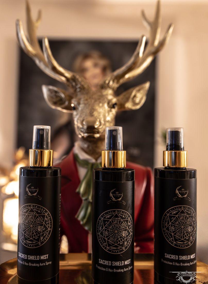 Three bottles of Sacred Shield Mist in front of a golden stag